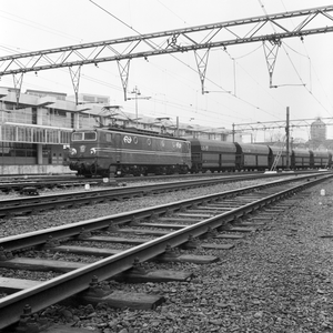 883134 Afbeelding van een electrische locomotief uit de serie 1300 van de N.S. met een erts- of kolentrein te Amsterdam C.S.